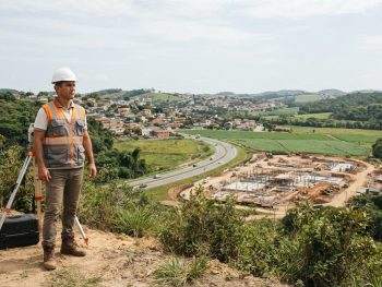 Topógrafo observando diferentes áreas de atuação da topografia, como construção civil, infraestrutura e agricultura.