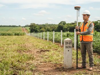 Profissional habilitado para regularização fundiária realizando levantamento com receptor GNSS RTK em propriedade rural.